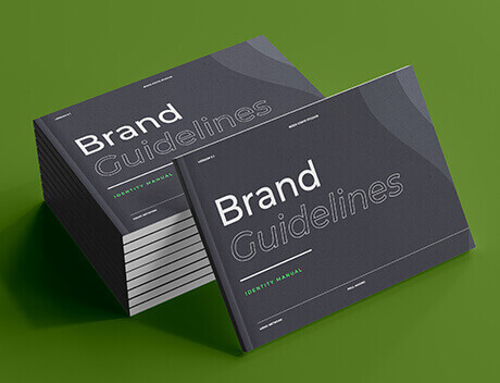 A stack of "Brand Guidelines" books with dark gray covers rests on a green surface, epitomizing the meticulous attention to detail that defines a leading Toronto Design Agency. Conte Studios