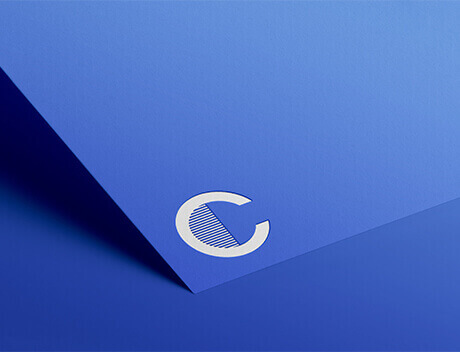 The sleek, stylized white "C" logo with diagonal lines rests elegantly on a blue paper surface, embodying the creative essence of Conte Studios, a renowned Toronto design agency. Conte Studios